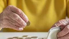 Starší osoba počítá mince, peněženka a finanční plánování pro důchodce.
